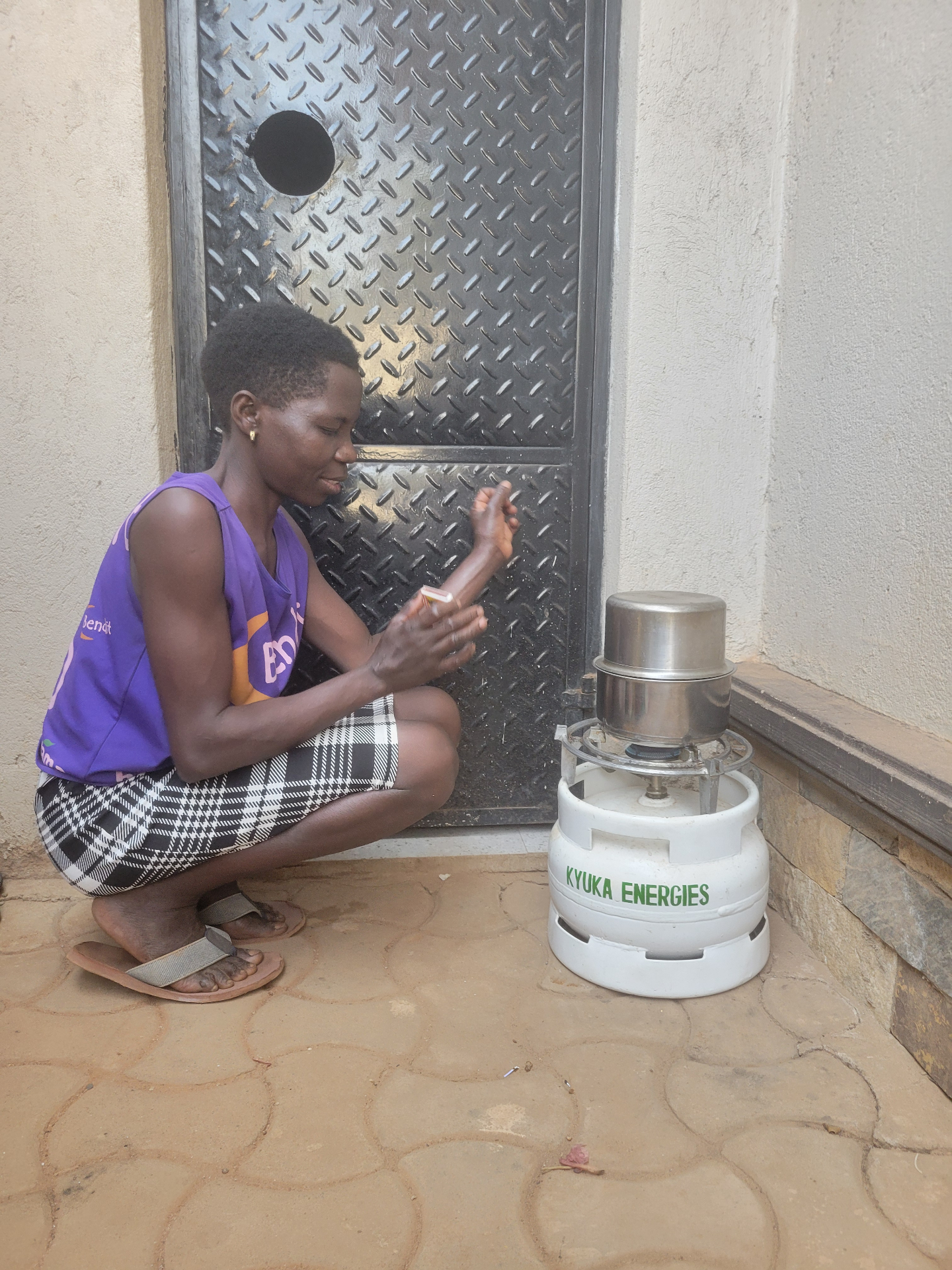 Mother lighting a Kyuka Energies LPG cylinder and stove at her doorstep
